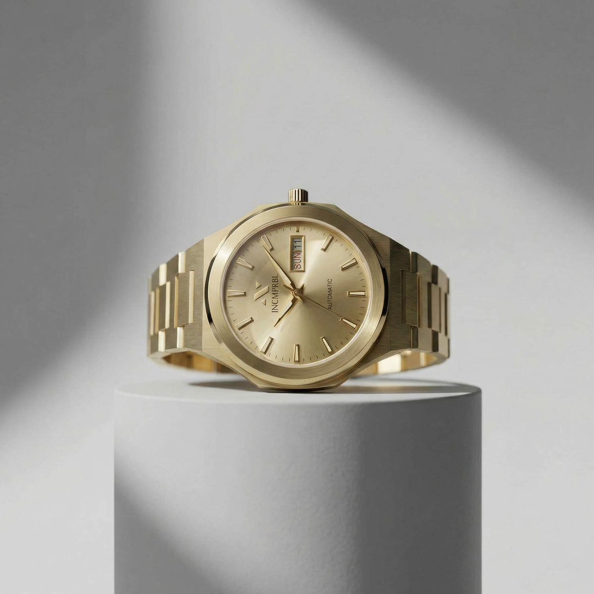 ascend aurel 36mm automatic link Gold watch on a gray cylindrical stand with a gray background